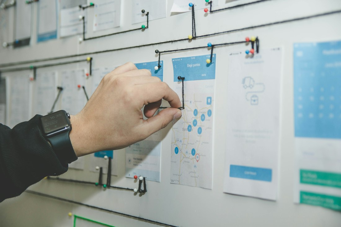 A hand arranging workflow notes on a wall board