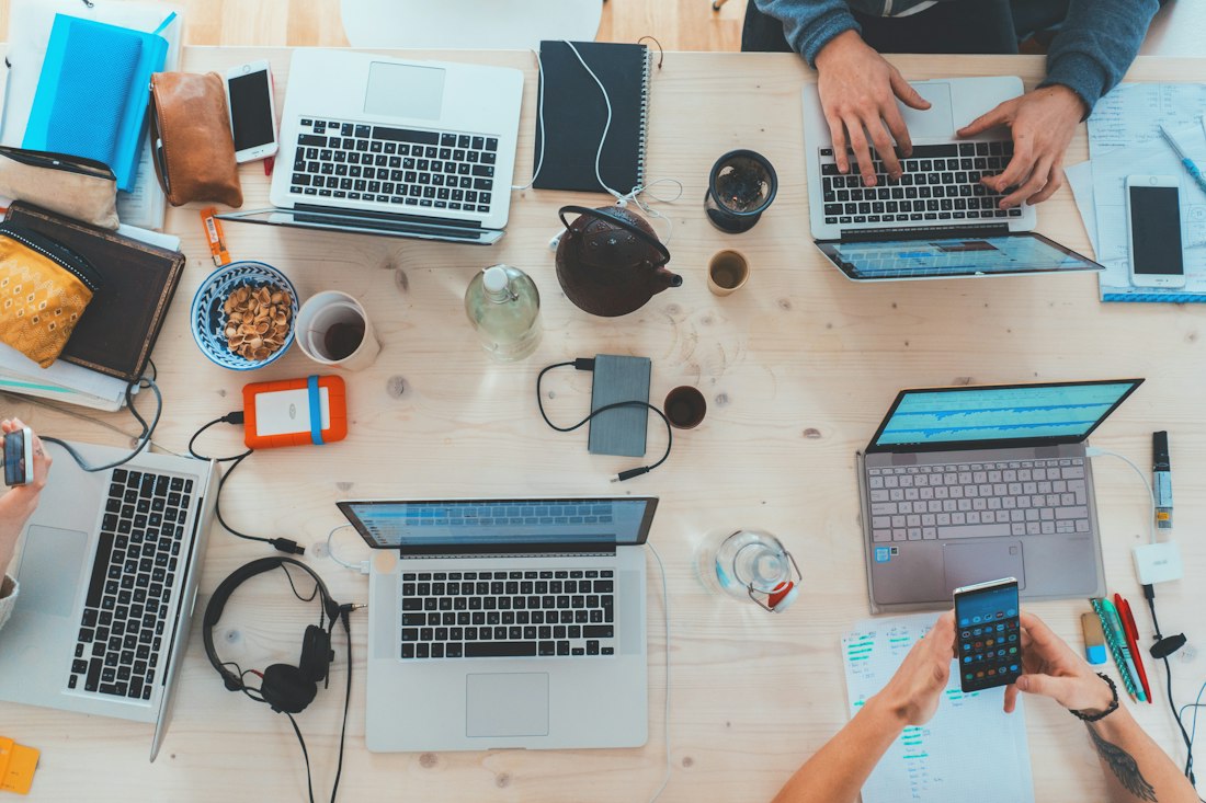 A team working at laptops around a shared desk