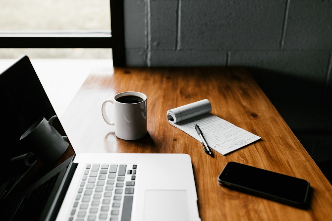 Laptop, notebook and coffee on a wooden desk